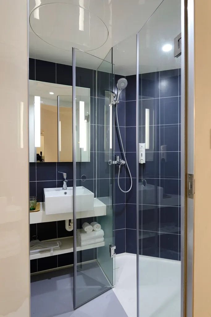 Shower with deep blue wall tile behind glass doors