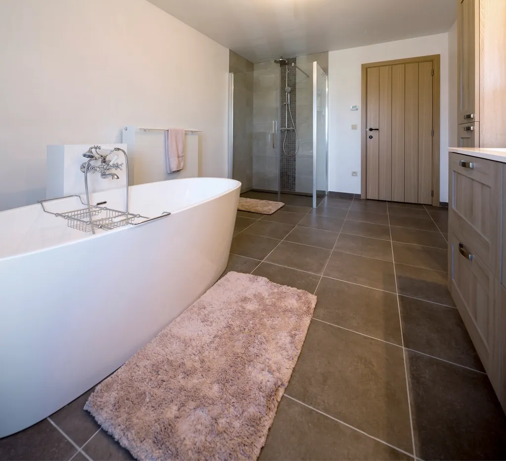 Bathroom with a soaker tub beside a tiled shower with wood tone tile