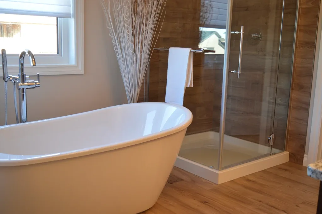 Bathroom with large gray floor tiles, double vanity and a tub