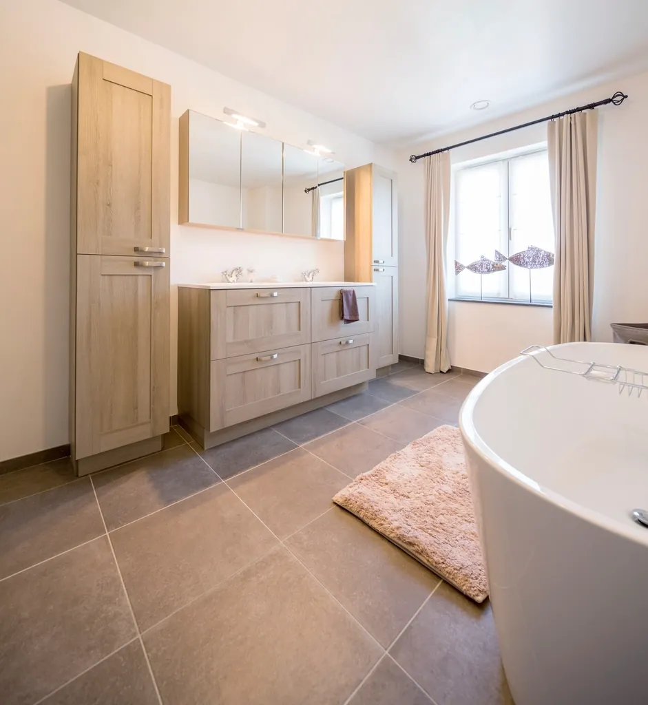 Bathroom with a double vanity under a large mirror and a tiled floor
