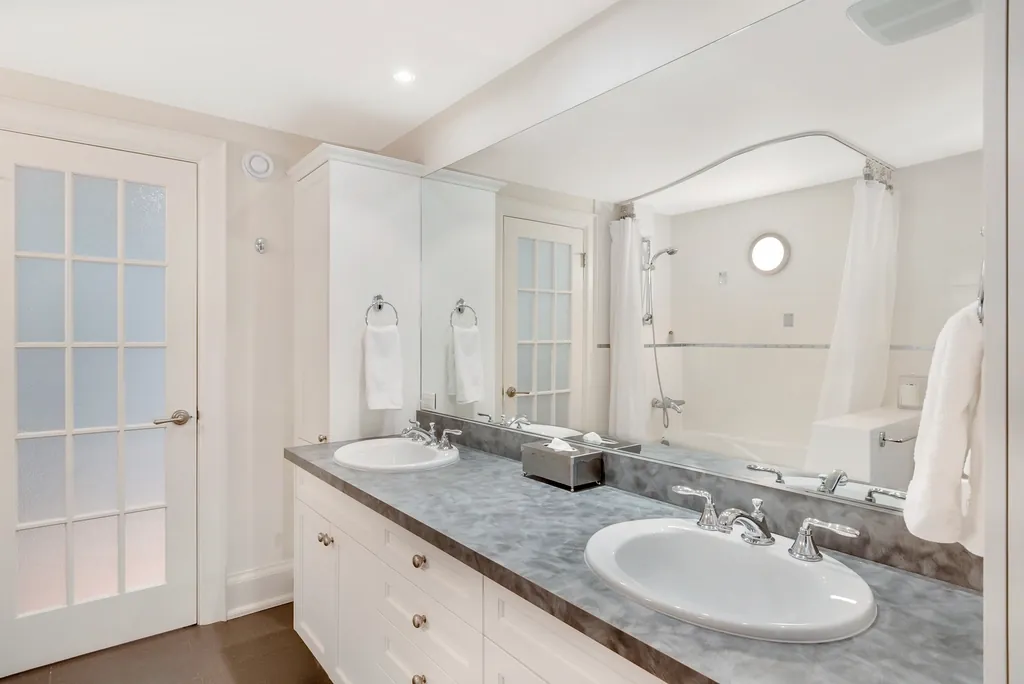 Soaking tub with a gray square tile wall behind it