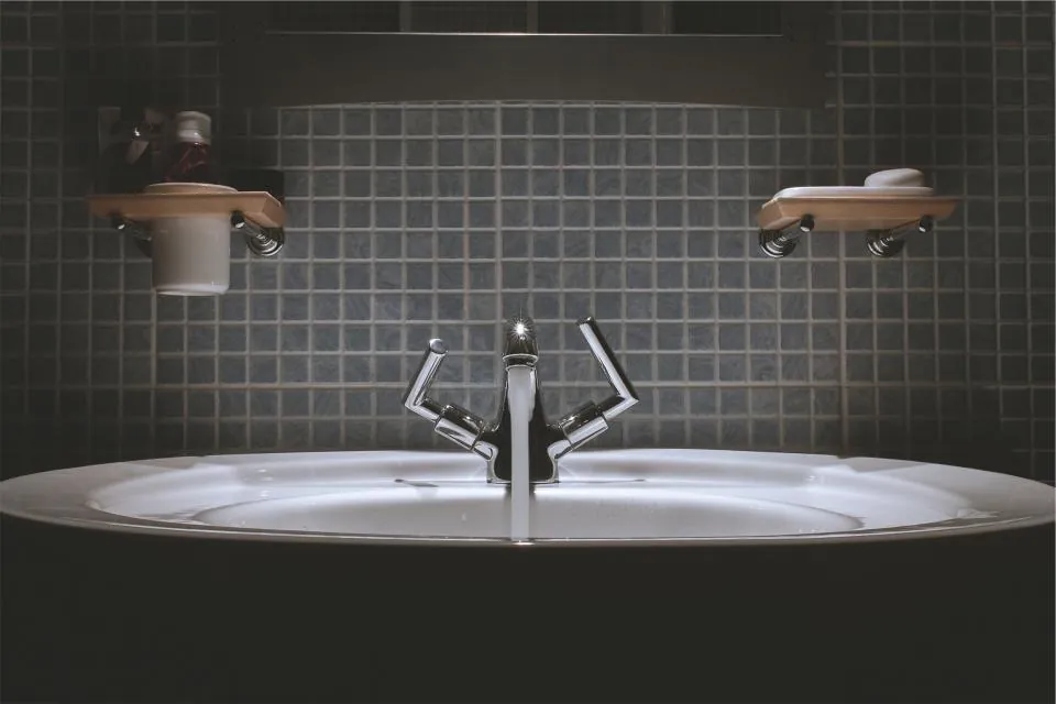 Bathroom with brown tile walls, glass shower and a stone vanity top
